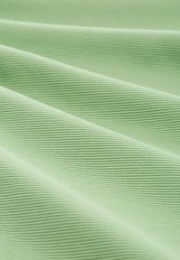 Tissu ribbé vert clair avec une texture douce, présentant de délicates lignes horizontales et une surface lisse, disposé en doux plis.