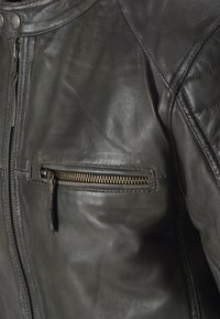 Schwarze Leder-Motorradjacke mit einer Reißverschlusstasche auf der Brust, gesteppten Schulterdetails und glatter Textur. Mit Metallhardware-Akzenten ausgestattet.