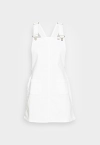 Vit denimförklädesklänning med justerbara remmar, silverfärgad hårdvara, två framfickor och rak passform. Slät, enkel textur.