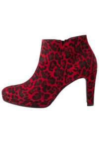 Bottine en daim rouge à imprimé léopard noir, talon haut, bout arrondi et fermeture éclair arrière. Elle présente une texture lisse et une légère semelle compensée.