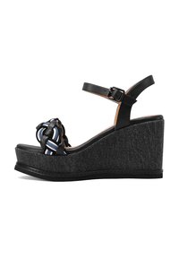 Sandalo con zeppa nera, in tessuto testurizzato, caratterizzato da un design annodato con accenti a righe e una cinturini alla caviglia regolabile.