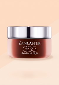 Lancaster 365 Skin Repair yön kremi, yuvarlak, pembe renkli bir kapta ve gümüş bir kapakla, ön kısımda net ve cesur bir marka ifadesi ile sunulmaktadır.