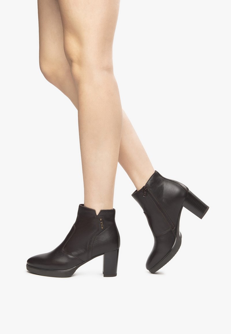 Black leather ankle boots with a block heel, side zipper, and a cut-out design at the collar. Smooth texture with minimal accents.