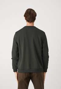 Felpa verde scuro con collo a giro, polsini e orlo a costine. Tessuto morbido, design semplice senza motivi o dettagli visibili.