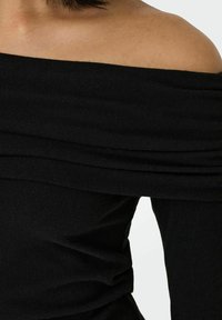 Top nero senza spalle realizzato in tessuto a coste, con texture arricciata lungo il scollo e un corpo aderente, che enfatizza una silhouette elegante.