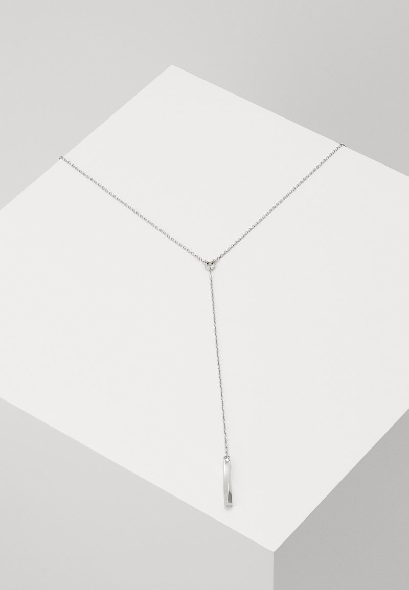 Collier pendentif en argent avec une chaîne délicate, présentant un design élancé et allongé ainsi qu'un charme minimaliste pointu en bas.