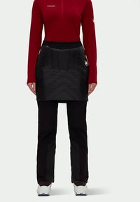 Melnā quiltēta svārku ar ševronu rakstu, apvienota ar sarkanu garām piedurknēm augšu. Iespējams, ar pieguļošu jostasvietu un melniem biksēm, kājām zila apavi.