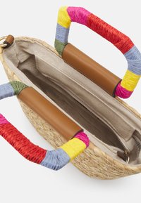 Sac fourre-tout en paille tissée avec intérieur en tissu beige, poche zippée et poignées enveloppées multicolores avec accents en cuir marron.