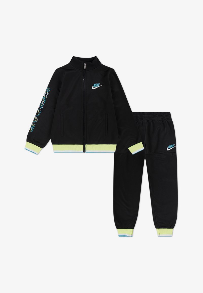 Melna Nike treniņtērps ar jaku ar rāvējslēdzēju un elastīgu jostasvērti. Iezīmēts ar zaļiem un ziliem akcentiem, logo uz krūškurvja un piedurknēm. Gluda auduma tekstūra.