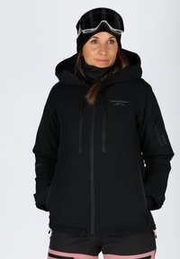 Black waterproof jacket with a hood, featuring zippered pockets, adjustable drawstrings, and a smooth texture. Includes a black beanie and ski goggles.