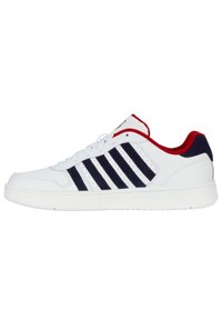 White athletic shoe with navy stripes, red accents on the collar, rounded toe, and textured white sole. Features lace-up design and perforations.