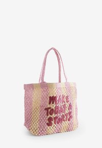 Bolsa tote tejida en rosa y beige con una superficie texturizada y la frase destacada "Haz de Hoy una Historia" bordada en rosa oscuro. Cuenta con dos asas.