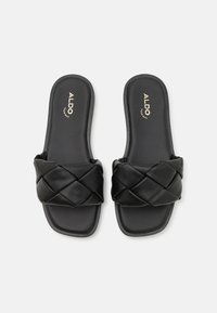 Sandali neri a scivolo realizzati in materiale liscio, con una fascia imbottita, suole piatte e un marchio discreto sulla soletta.