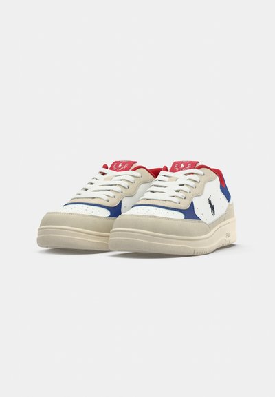 Vita och blå sneakers med en beige sula, som har röda detaljer, snörning och perforerad dekoration på tåboxen.