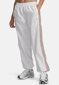 Witte sportbroek met een elastische tailleband, voorzien van pastelroze en beige zijstrepen. Gemaakt van lichtgewicht, soepel materiaal.