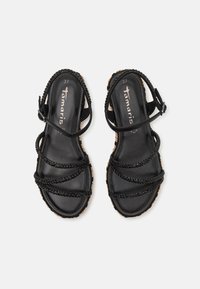 Sandales noires à lanières avec des accents tressés, semelle en liège et bride de cheville réglable. Taille 37, texture lisse, design minimaliste.