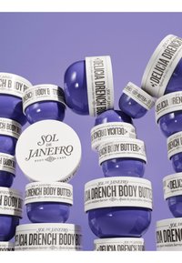 Mehrere lila runde Behälter von Sol de Janeiro Delicia Drench Body Butter mit weißen Deckeln und Etiketten auf lila Hintergrund.