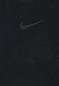 Top nero in tessuto costellato con logo Nike swoosh grigio scuro liscio posizionato centralmente. Texture morbida con scollo rotondo.