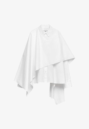 Asymmetrisk vit skjorta med knappar, bred krage och ett draperat överlägg som sträcker sig ojämnt på ena sidan.