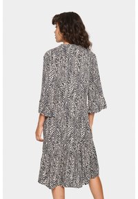 Knieumhangkleid mit einem schwarz-weißen Zebra-Muster, Rüschensäumen und einem gestuften Design, aus leichtem Stoff gefertigt.