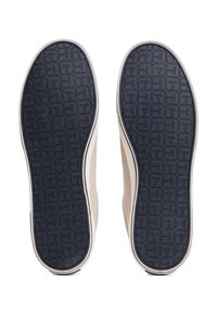 Sneakersulor med en texturerad navy gummibotten med ett geometriskt mönster och en beige canvas ovandel, accentuerad med en vit kant.