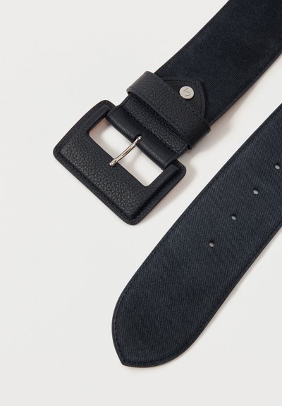 Μαύρη υφασμάτινη δερμάτινη ζώνη με παραλληλόγραμμη αγκράφα και πολλαπλές οπές προσαρμογής σε απλό ανοιχτό φόντο.