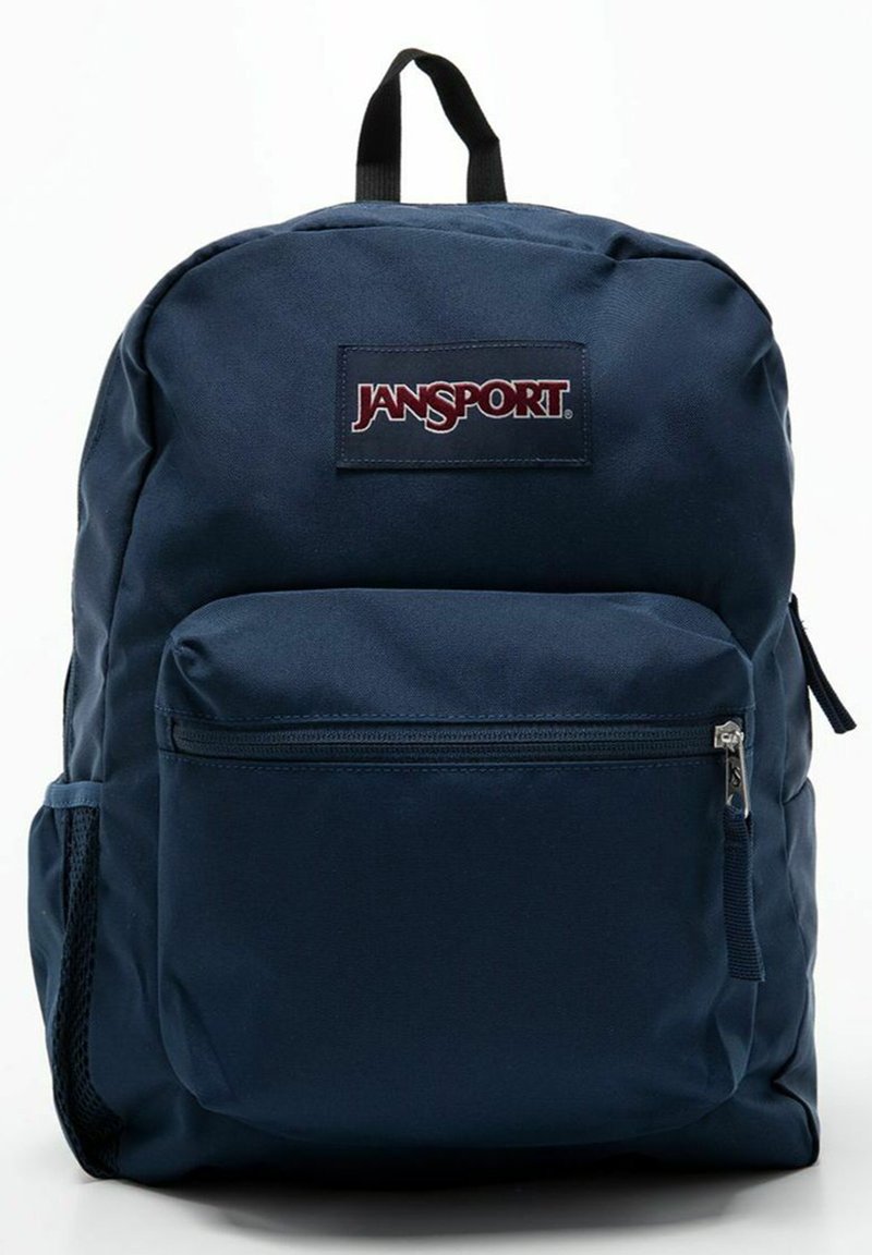 Zaino Jansport blu navy realizzato in tessuto resistente, dotato di un compartimento principale, tasca frontale con zip, tasca laterale in rete e patch con logo.