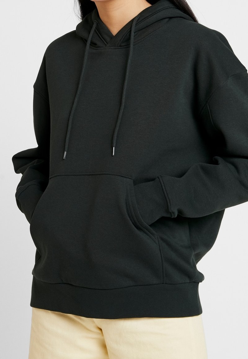 Sudadera negra con capucha ajustable y un bolsillo frontal. Fabricada en una suave mezcla de algodón con puños y dobladillo acanalados para un ajuste relajado.