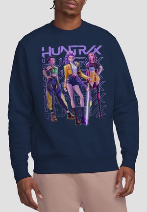 Marineblaue Sweatshirt mit einem Grafik von drei bunten Charakteren; leuchtende Farben, unterschiedliche Outfits und Textüberlagerung "HUNTRX."