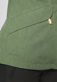 Green jacket with a textured surface, featuring a front pocket and tan hardware accents. Branding visible near the hem: "Ceplex Active."