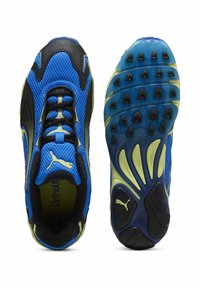 Chaussures de sport bleues et noires avec une tige en maille, des accents jaunes et une semelle en caoutchouc texturée présentant des motifs de grip distincts.