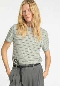 Grå stribet T-shirt med korte ærmer, lavet af blødt materiale. Sammen med højtaljede grå bukser med et sort bælte.