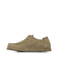 Chaussure en daim beige clair avec un bout rond, un laçage et une semelle texturée. Présente une branding discrète sur le talon.