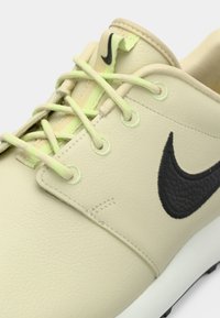 Μπεζ συνθετικό αθλητικό παπούτσι με μαύρο λογότυπο Nike, ανώτερο μέρος από υφή δέρματος και γαλάζια κορδόνια. Διαθέτει επενδεδυμένο γιακά και λαστιχένια σόλα.