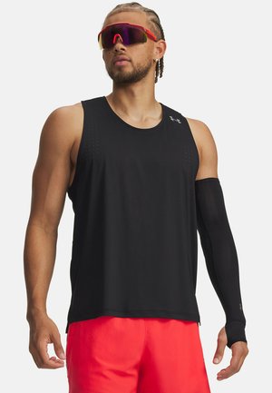 Čierny športový tank top s perforovanými detailmi, doplnený o čierny rukáv na ruke. Svetlé červené šortky a zrkadlové slnečné okuliare dotvárajú vzhľad.