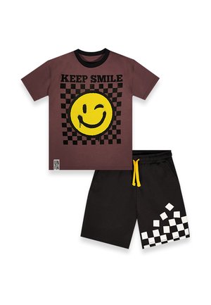Camiseta marrón con cuello negro, emoticono amarillo guiñando el ojo y texto "KEEP SMILE" sobre diseño de cuadros negros, combinada con pantalones cortos negros con cuadros blancos.