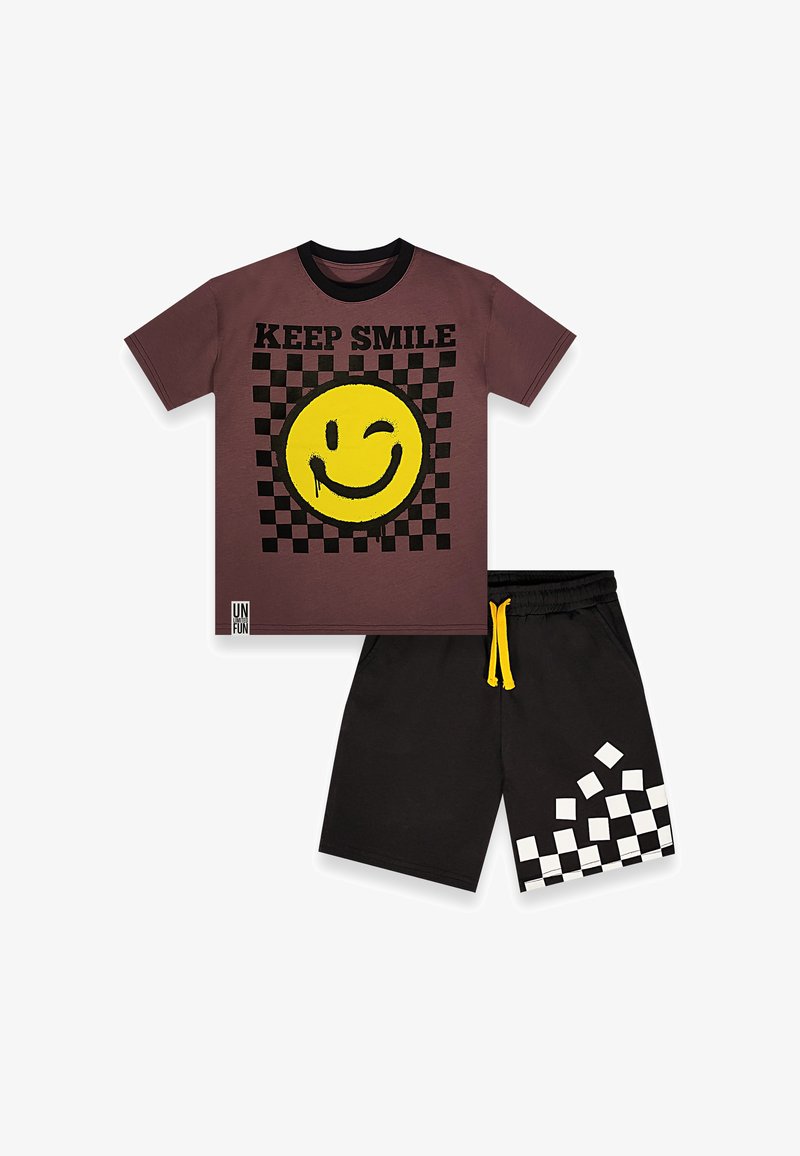 Brun t-shirt med sort krave, gul blinkende smiley og teksten "KEEP SMILE" over et sort ternet mønster, kombineret med sorte shorts med hvide firkanter.