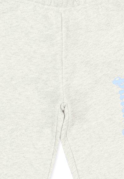 Tissu gris clair avec couture centrale et petite fente près du bas, laissant apparaître une partie de texte bleu clair sur le côté.