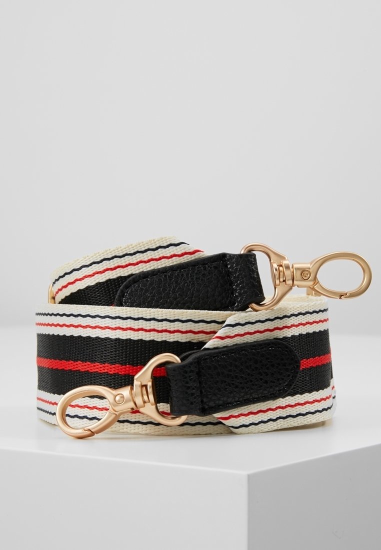 Sangle de sac en tissu rayé noir, blanc et rouge avec des accents en cuir noir et des fermoirs pivotants en métal doré aux deux extrémités.