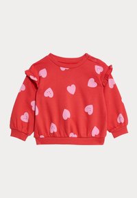 Rød sweatshirt med pink hjerte mønstre, flæser på skuldrene og elastiske manchetter. Har en samlet kant og trykknaplukning på skulderen.
