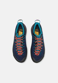 Scarpe da arrampicata in suede blu scuro con suole in gomma nera, dotate di lacci arancioni vivaci e fodera in mesh turchese.