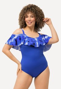 Modré jednodílné plavky s volnými rukávy, které odhalují ramena, v modro-fialovém maskáčovém vzoru, s nastavitelnými ramínky a hladkou texturou.