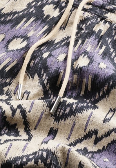Mönstrad tyg med svarta, lila och beige färger, med en texturerad yta. Två beige dragsnören med silverändar syns.