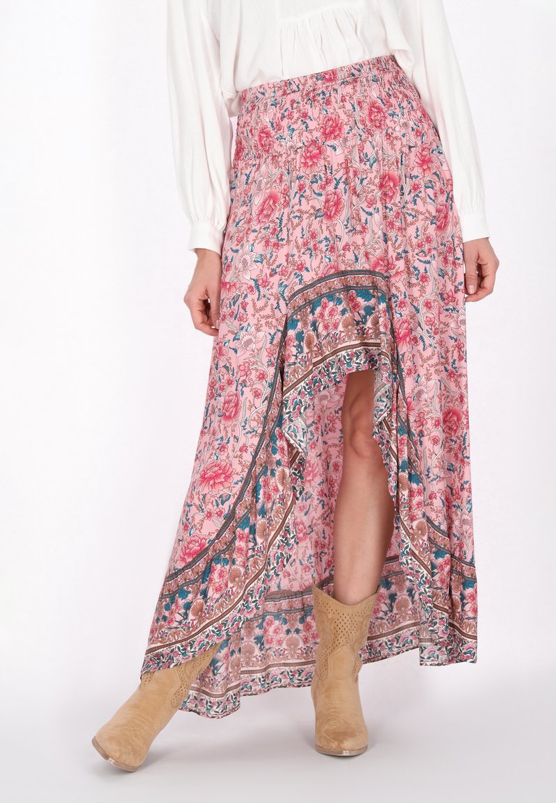 Maxi-Rock in Hellpink mit Blumenmuster, mit Rüschenbund, asymmetrischem Saum und dekorativem Rand; kombiniert mit beigefarbenen Ankle Boots.