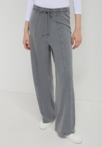 Pantalons de survêtement larges gris clair avec une taille élastique et un cordon de serrage. Fabriqués à partir d'un tissu doux avec des coutures le long des côtés.