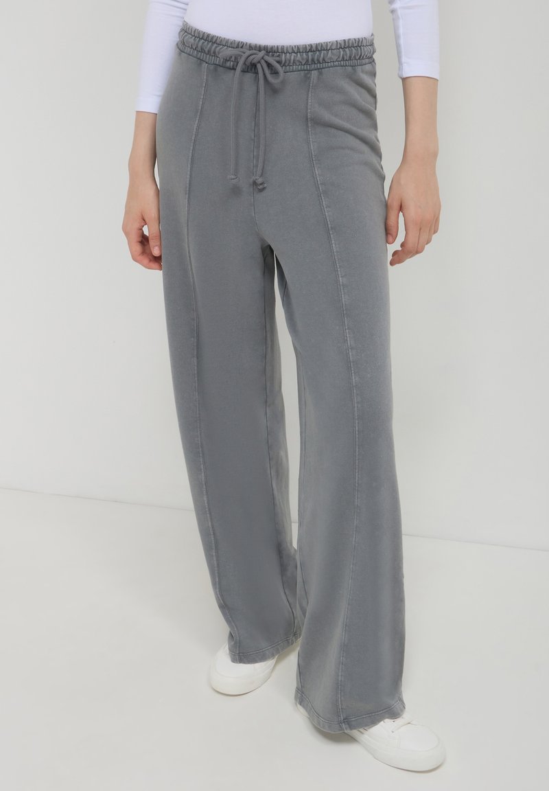 Pantalons de survêtement larges gris clair avec une taille élastique et un cordon de serrage. Fabriqués à partir d'un tissu doux avec des coutures le long des côtés.