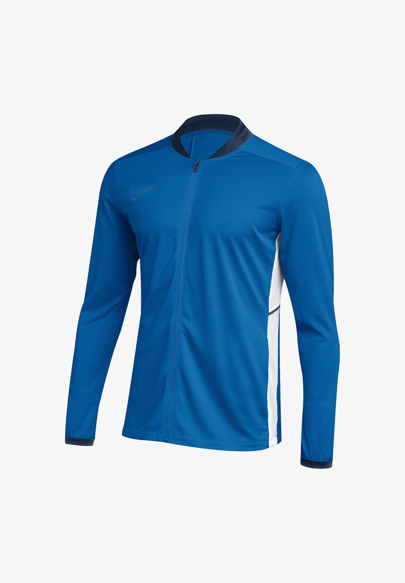 Veste de sport bleue zippée intégralement, manches longues, panneaux latéraux blancs, col et poignets noirs, avec un petit logo Nike sur la poitrine.