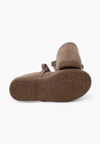 Braune Wildlederschuhe mit runder Zehe, verstellbarem Riemen und strukturiertem Gummisohle mit floralem und herzförmigem Muster.