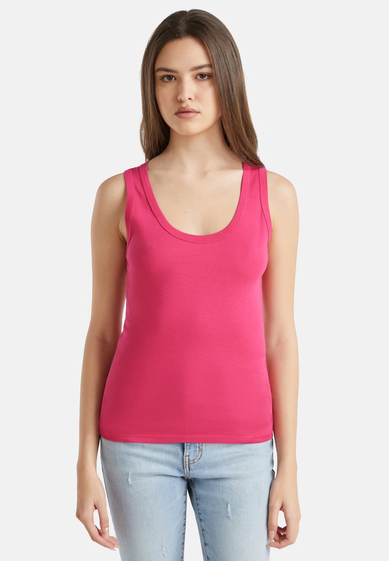 Débardeur rose ajusté avec un décolleté arrondi et des bretelles larges, en tissu extensible, associé à un jean bleu clair déchiré.