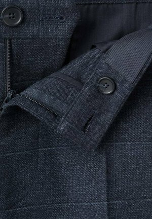 Blazer di lana scura con tessuto testurizzato, due bottoni, tasca con zip e fodera cucita. Sottile motivo a quadri visibile.